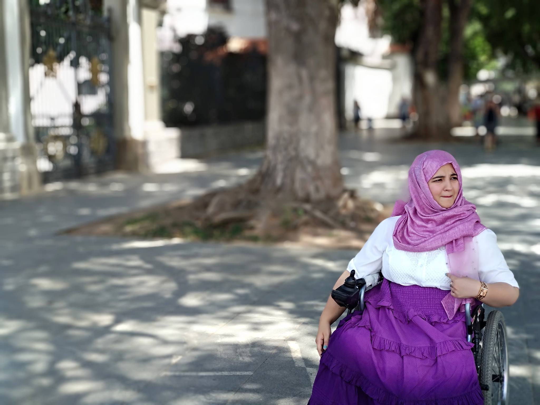 Tanzila Khan is on wheelchair wearing dark purple skirt, white top and a purple headscarf.
